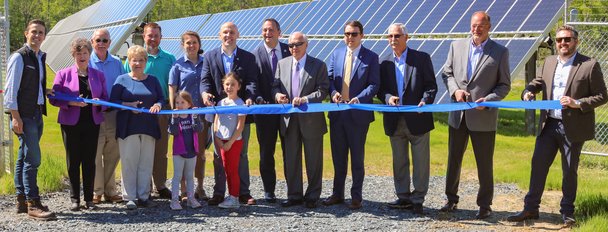 Group cuts ribbon in front of solar panels