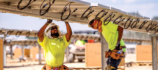 Construction workers wiring solar panels at a site