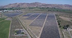 A solar farm is seen from above with mountains in the background