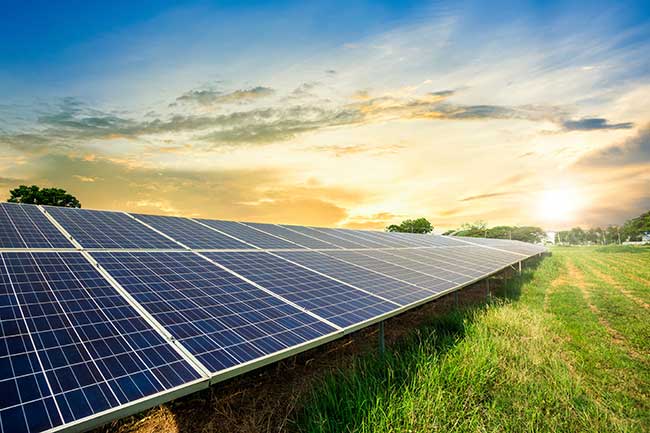 Elevated view of a large solar farm with a blue sky and a few clouds