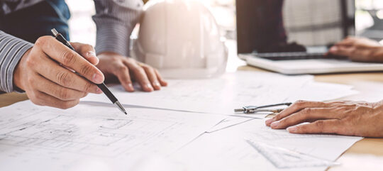 A drafting table with engineering plans for an upcoming development site