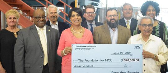 A group of people gather around an oversized check 