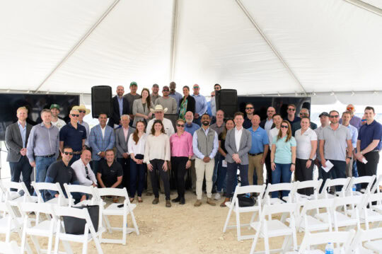 A large group of people pose in front of a stage