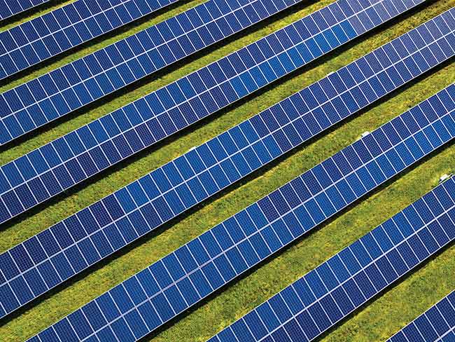 Aerial shot of solar farm with green freshly cut grass