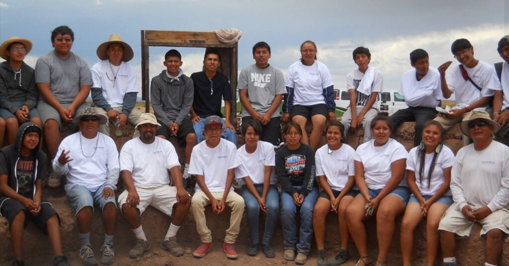 A large group of people pose facing the camera in two rows